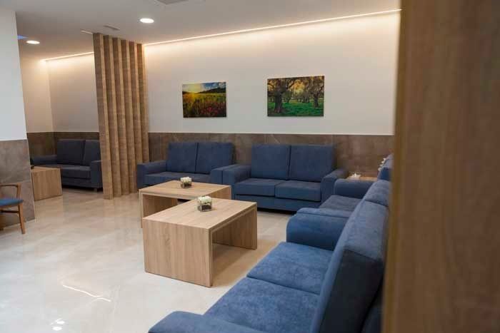 Una sala de estar con sofás azules, mesas de café y sillas.