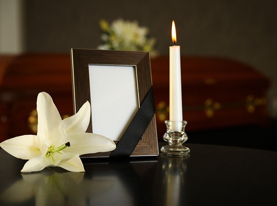 Un marco de fotos con una cinta negra y una vela sobre una mesa.