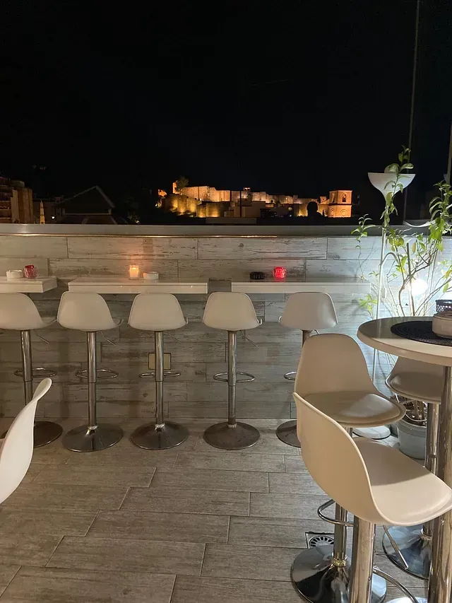 Una fila de mesas y sillas en un restaurante por la noche.