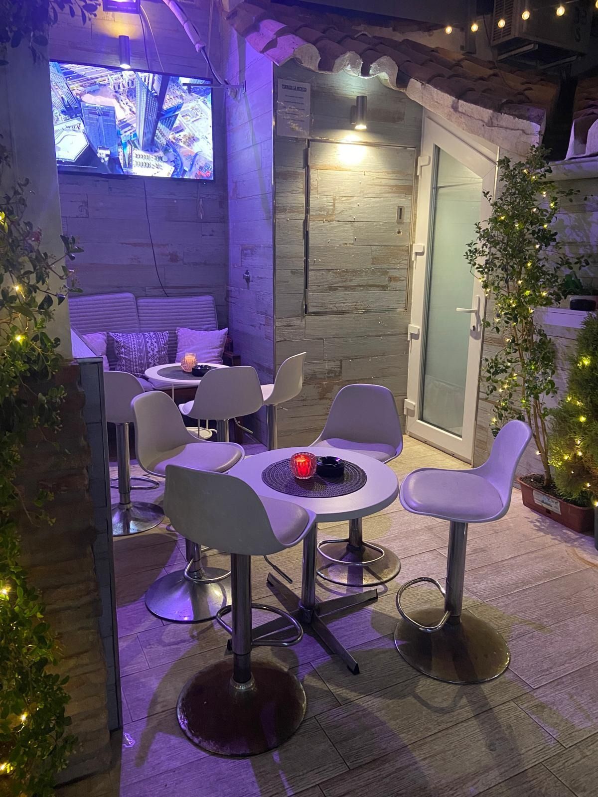 Una habitación con mesas y sillas y un televisor en la pared.
