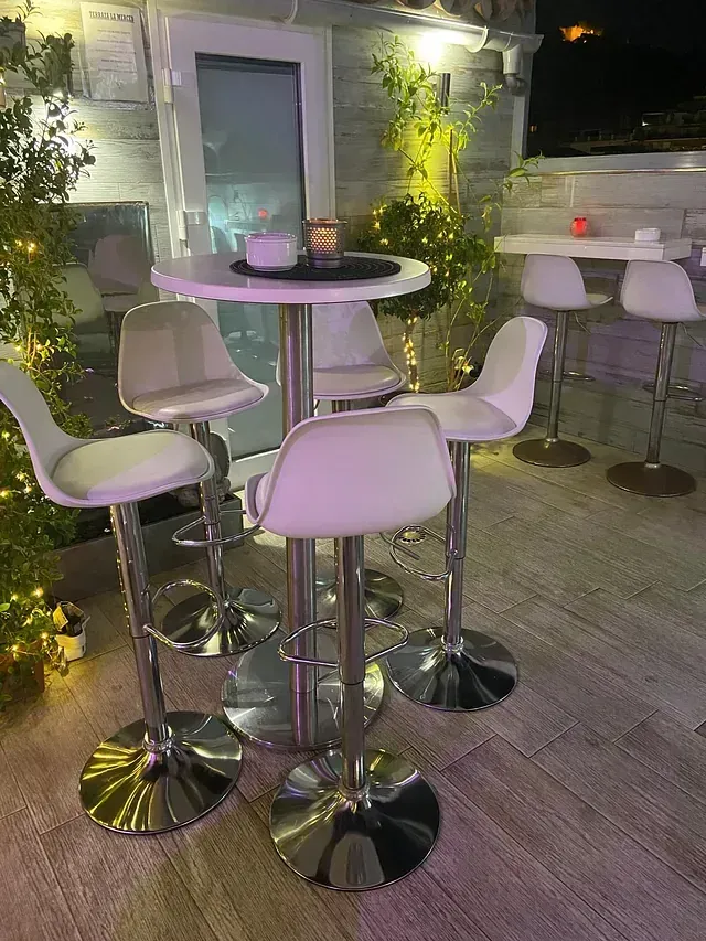 Un grupo de taburetes blancos están sentados alrededor de una mesa en un restaurante.