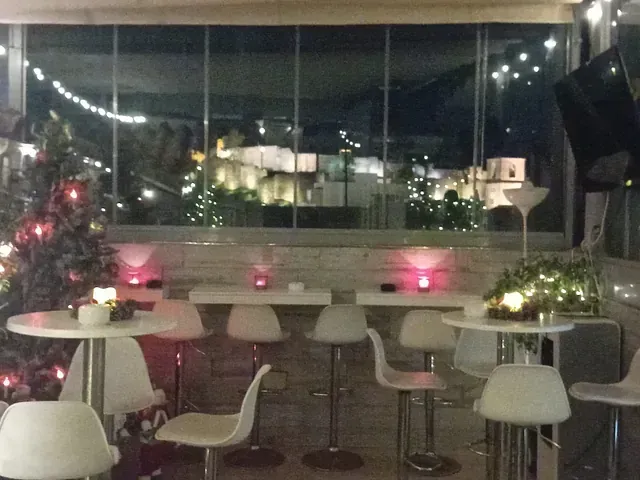 Una habitación con mesas y sillas y un árbol de Navidad al fondo.