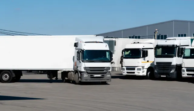 Una fila de camiones semirremolques blancos están estacionados en un estacionamiento.