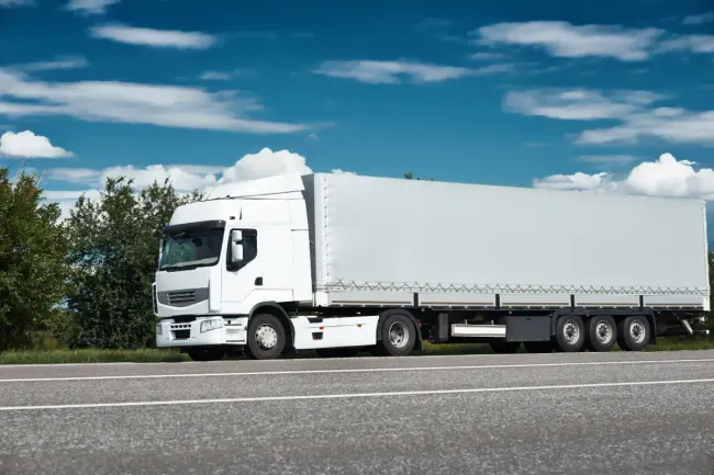 Un camión semirremolque blanco circula por una autopista.
