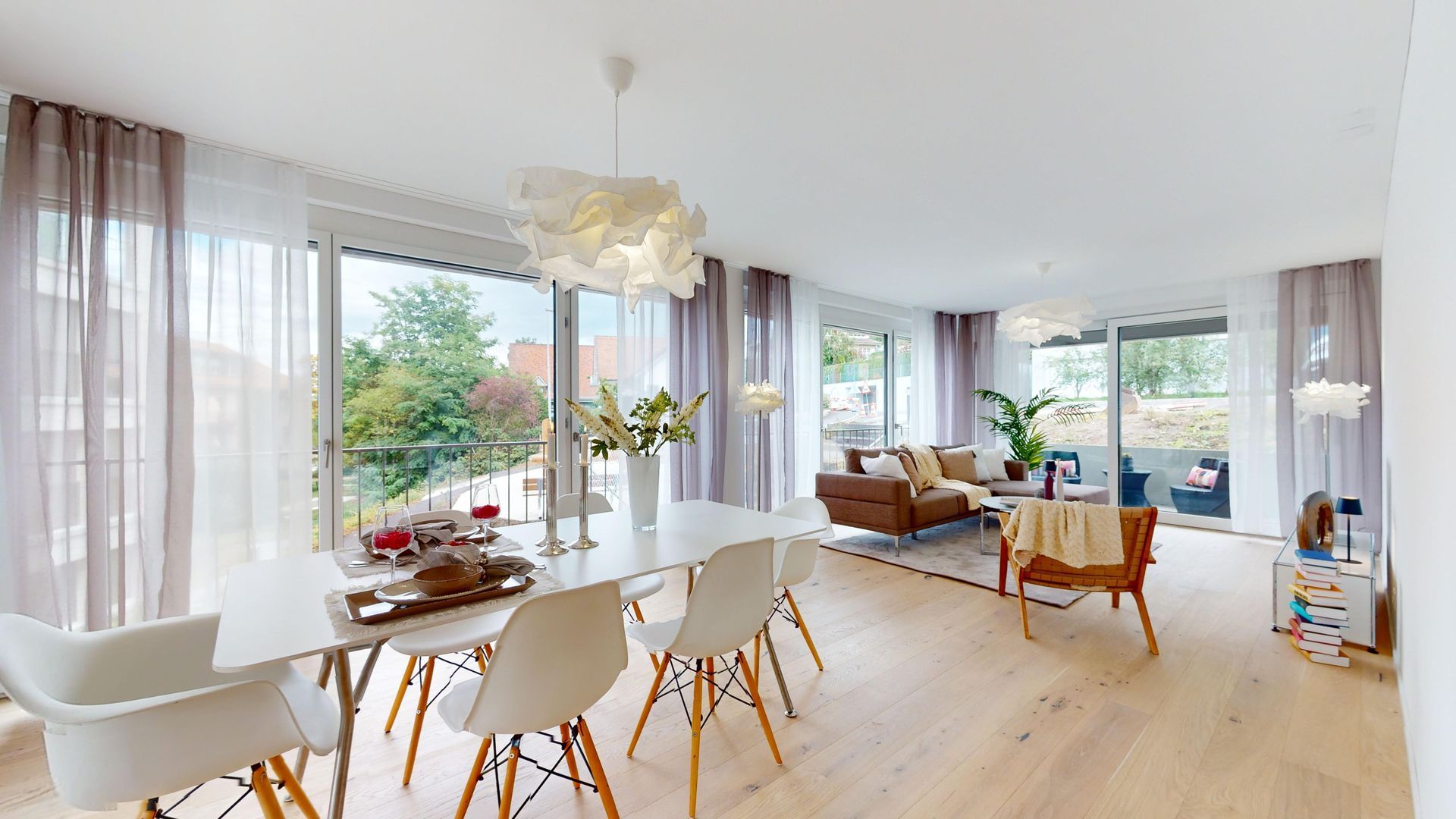 Die Hände deuten auf ein kleines Modellhaus auf einem Schreibtisch mit Dokumenten, das ein Treffen im Immobilien- oder Versicherungsbereich symbolisiert.