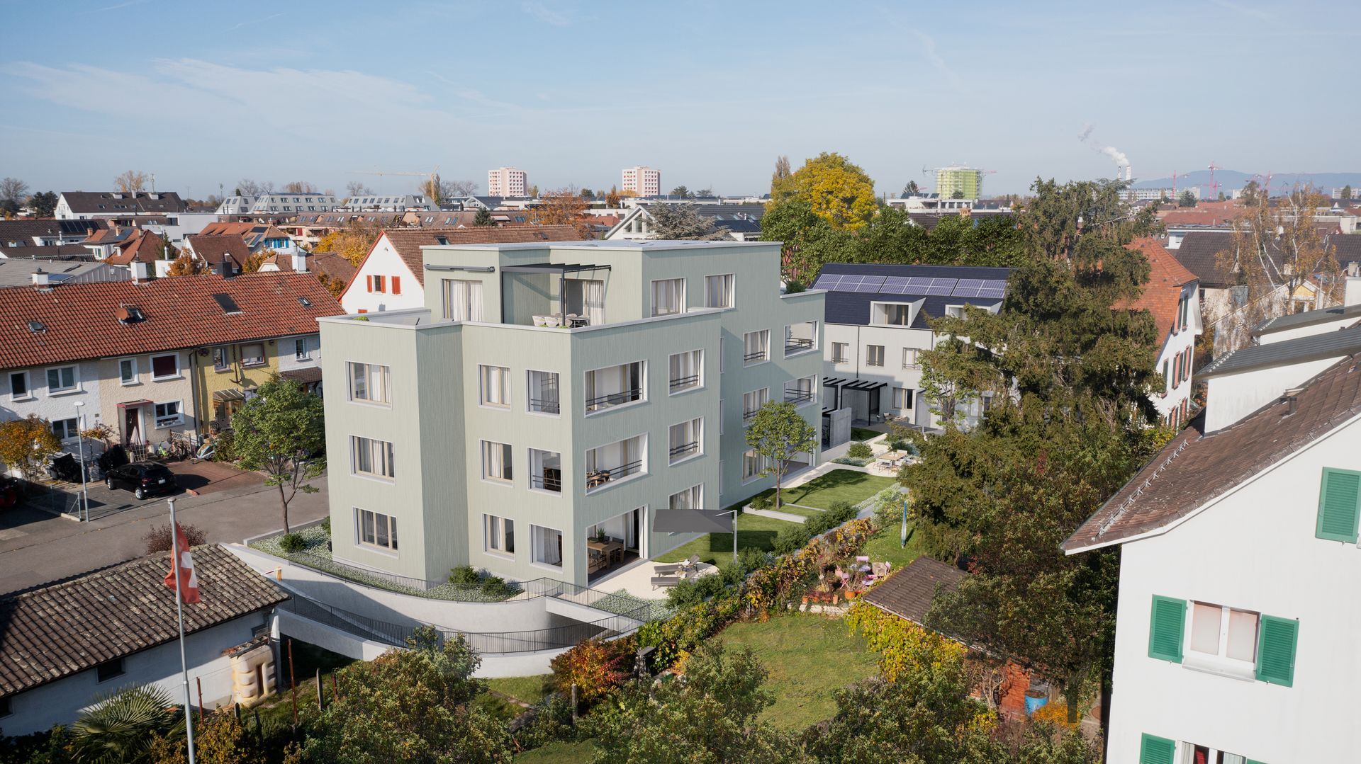 Ein modernes, hellgrünes dreistöckiges Wohnhaus mit symmetrischen Fenstern, in der Nähe einer Rasenfläche und eines Parkplatzes.