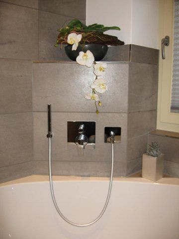 Eine Badewanne mit Duschkopf und einer Vase mit Blumen darauf.