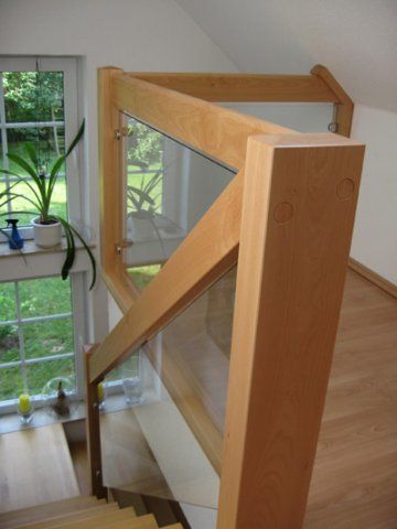 Eine Holztreppe mit Glasgeländer und Fenster