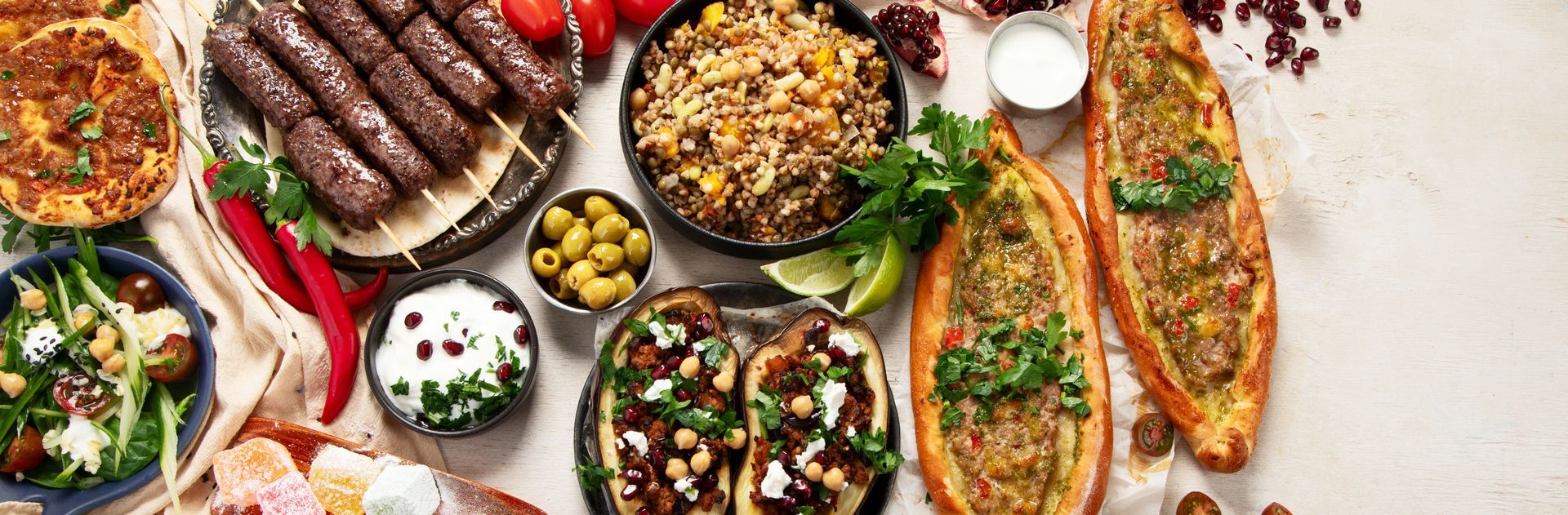 Vue plongeante sur un buffet méditerranéen composé de brochettes grillées, de pains plats, de riz, d'olives, de sauces et d'une salade fraîche.
