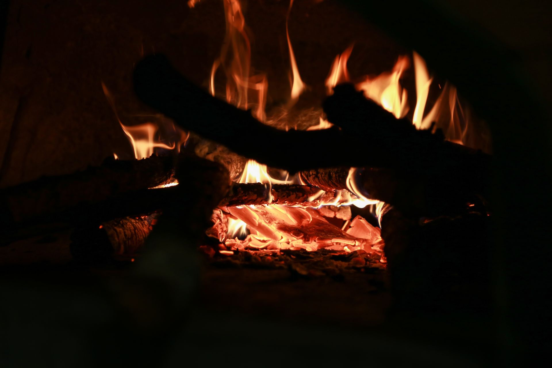 Des flammes d'un orange vif et des braises incandescentes brûlent parmi plusieurs bûches.