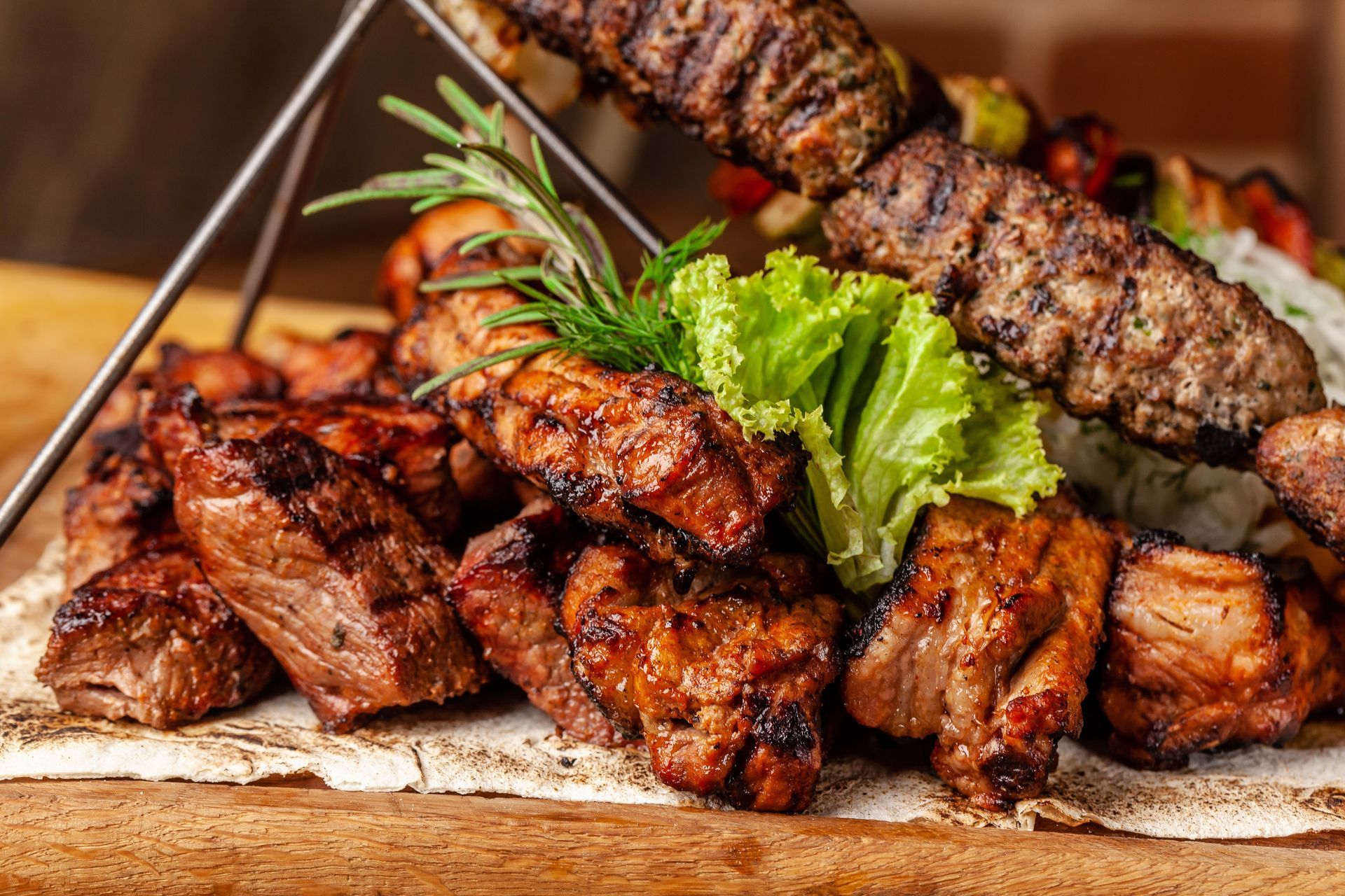 Un plateau en bois garni de viandes grillées assorties, notamment des brochettes et des morceaux de viande.