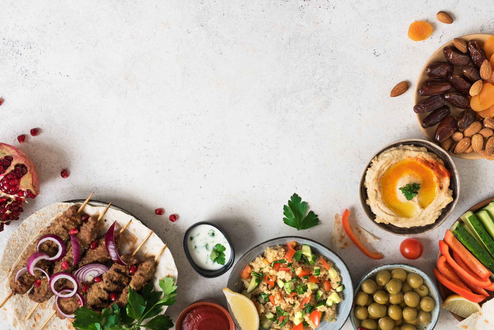 Une variété de plats méditerranéens, notamment des brochettes grillées, du houmous, des olives et des dattes.