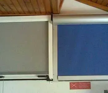 Duas persianas estão penduradas na parede, uma ao lado da outra.