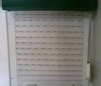 Um close de uma veneziana branca em uma janela.