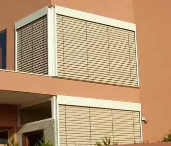 Uma casa com duas janelas com persianas.