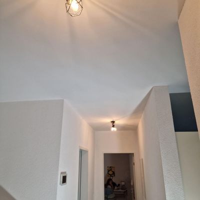 Flur mit weißen Wänden und Decke, beleuchtet von zwei Pendelleuchten.