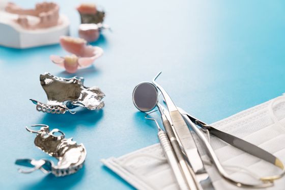 Des instruments dentaires et un miroir à côté d'une rangée de moules dentaires sur fond bleu