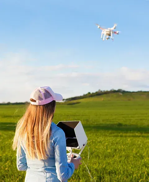 Una mujer está volando un dron en un campo.
