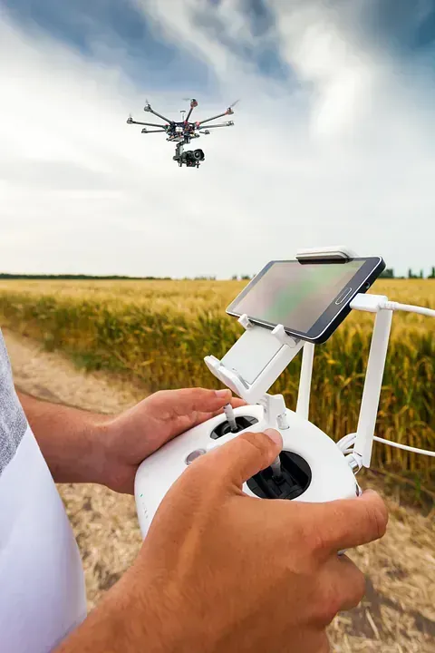 Una persona está volando un dron en un campo mientras sostiene un control remoto.