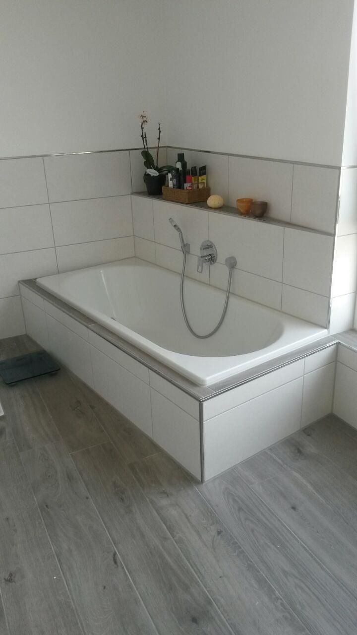 Eine Badewanne in einem Badezimmer mit Holzboden.