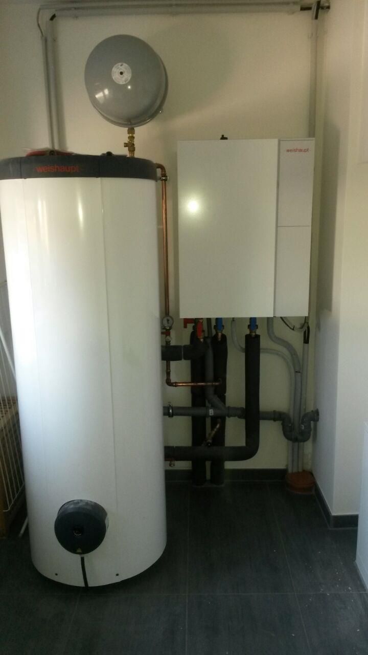 In einem Raum steht ein weißer Warmwasserbereiter neben einem weißen Boiler.