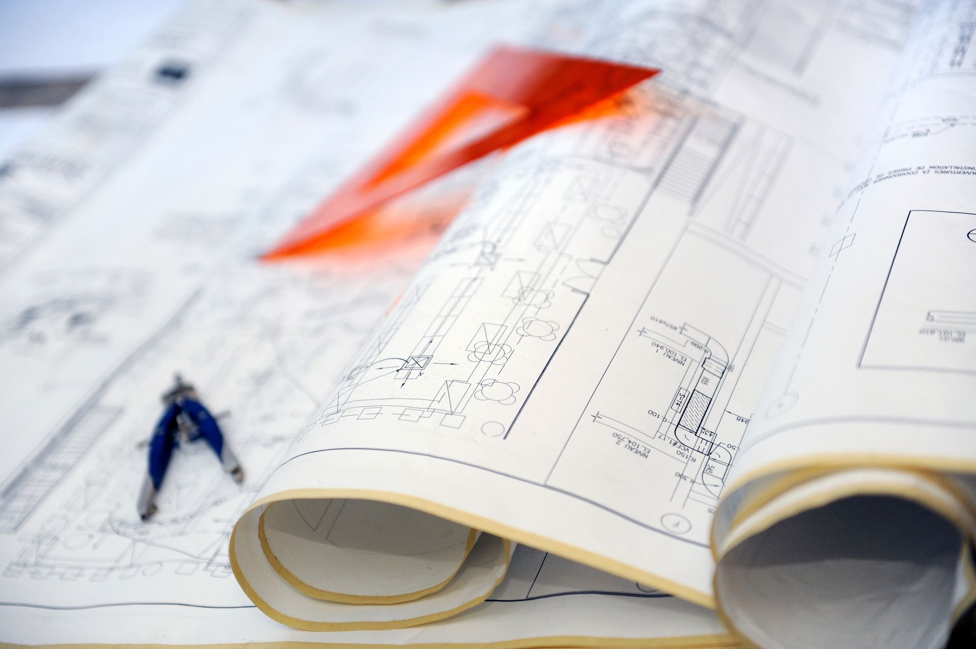 Des plans architecturaux avec un compas et une équerre dessus.
