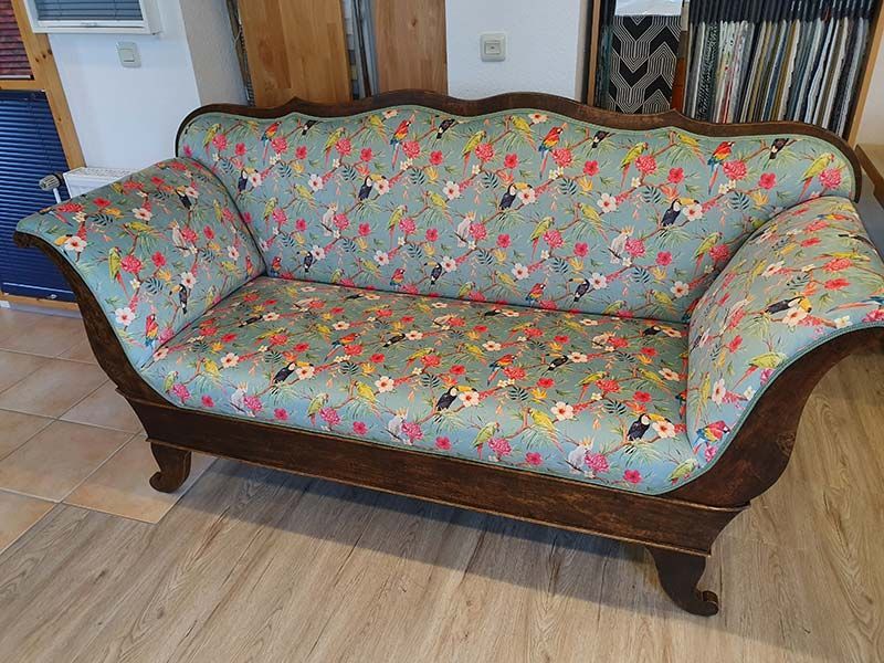 Auf einem Holzboden steht ein Sofa mit Blumenmuster.