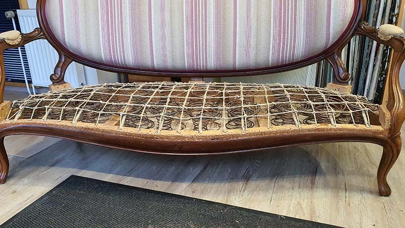 Auf einem Holzboden steht neben einem Teppich ein Sofa.