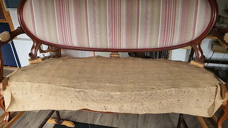 Auf einem Holzboden steht ein Sofa mit gestreiftem Kissen.