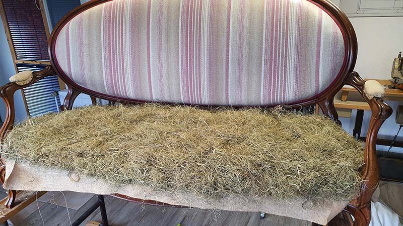 Auf einem Holzboden steht ein Sofa mit gestreiftem Kissen.