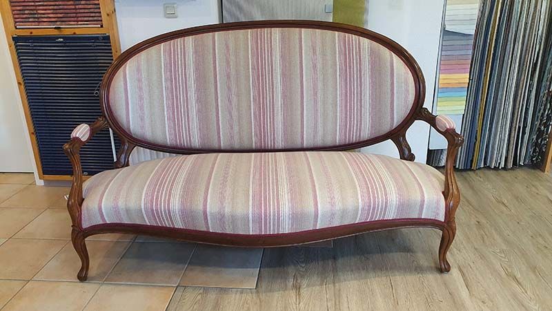 In einem Zimmer steht ein gestreiftes Sofa auf einem Holzboden.