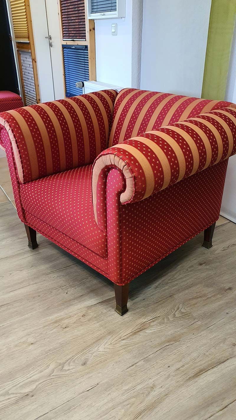 Auf einem Holzboden steht ein rot und orange gestreifter Stuhl.