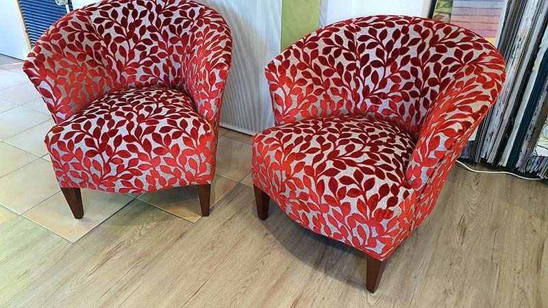 Zwei rote Stühle stehen nebeneinander auf einem Holzboden.