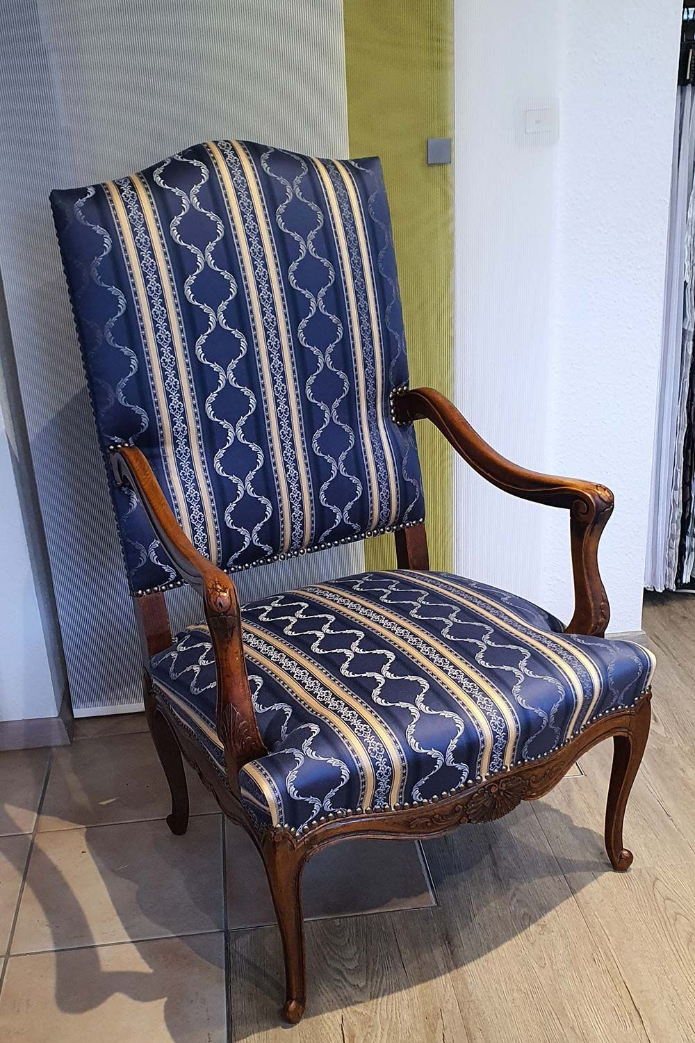 Auf einem gefliesten Boden steht ein blau-gold gestreifter Stuhl.