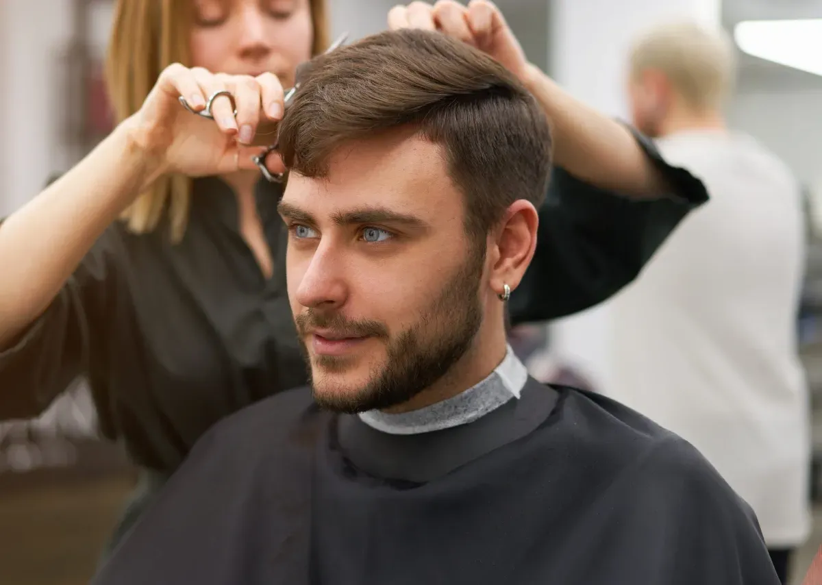 Peluquero cortando el pelo con tijeras y peine.