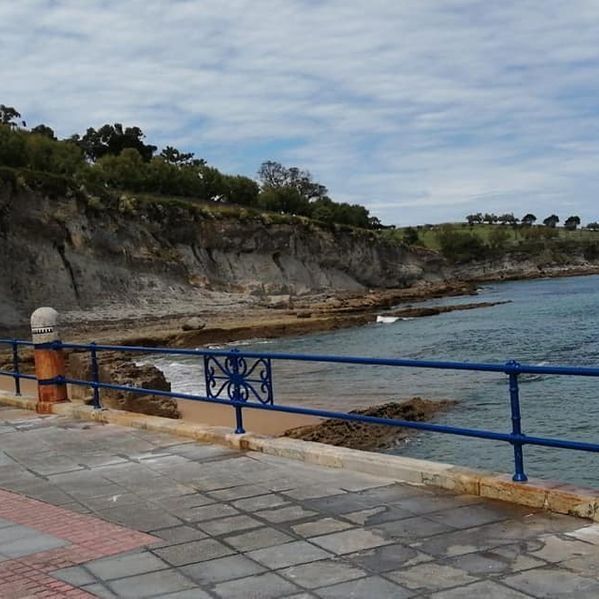 Una barandilla azul a lo largo de una pasarela que conduce al océano.