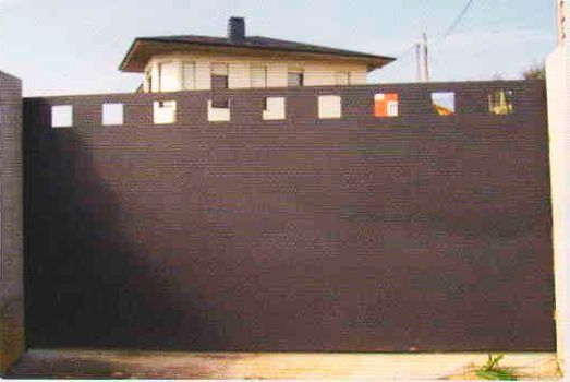 Una valla negra con una casa al fondo.