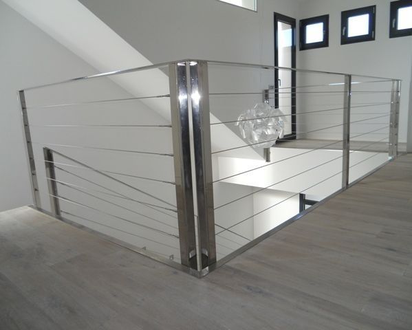 Una escalera con barandilla de acero inoxidable y barandilla de vidrio.