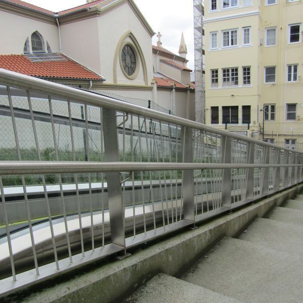 Una escalera con barandilla de metal y una iglesia al fondo.