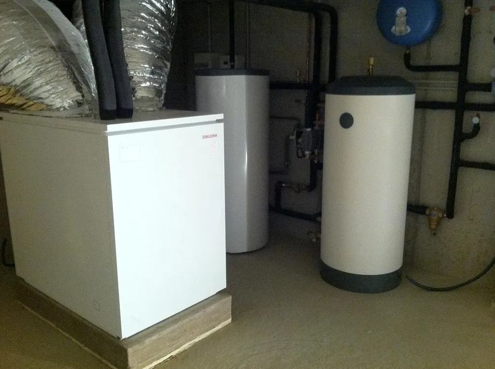 Local technique blanc avec chauffe-eau et équipements mécaniques.