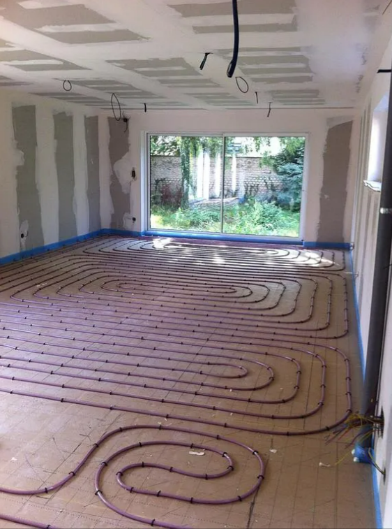 Tuyaux de chauffage au sol installés dans une pièce avec une grande fenêtre.