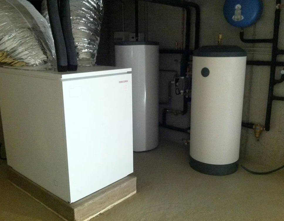 Une buanderie avec un système de chauffage, des chauffe-eau et des canalisations.