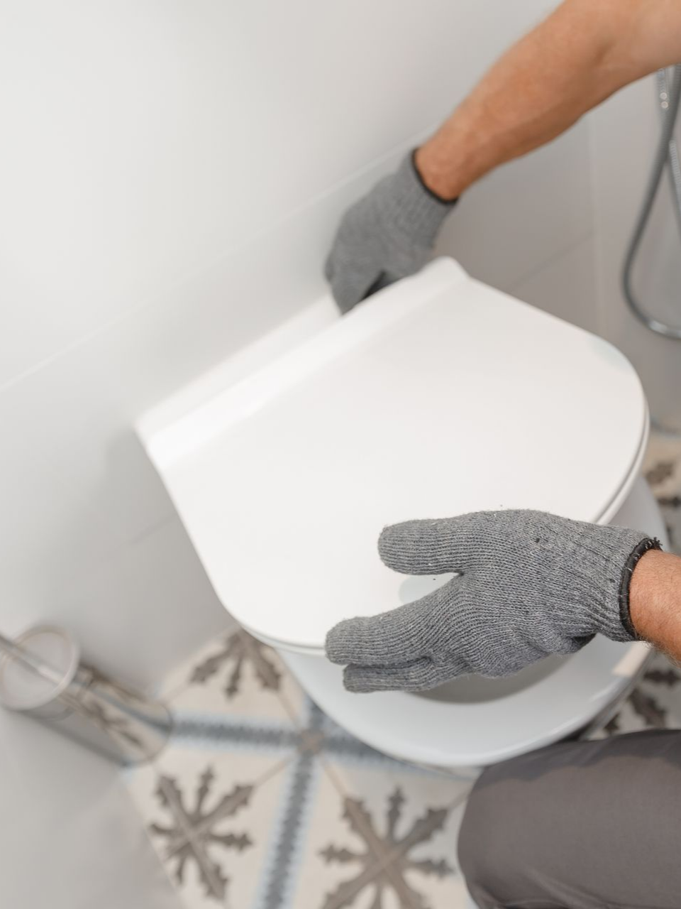 Une personne portant des gants installe un abattant de toilette blanc.