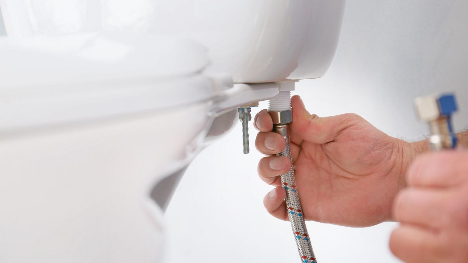 Personne raccordant une conduite d'alimentation en eau à un réservoir de toilettes.
