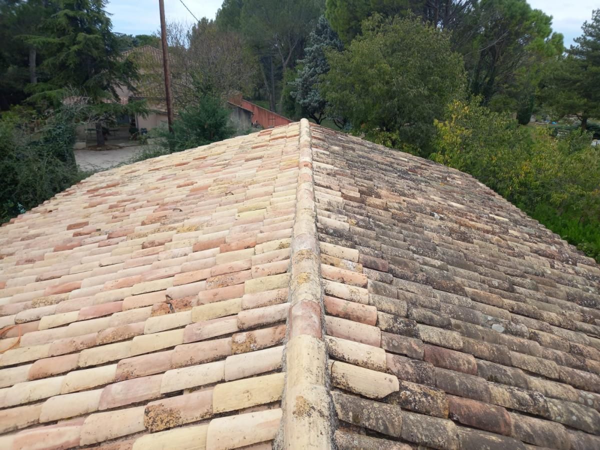 Un homme pose des tuiles sur un toit en bois.