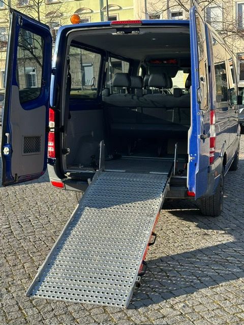 Eine Pflegekraft hilft einer älteren Person im Rollstuhl beim Einsteigen in ein Auto.