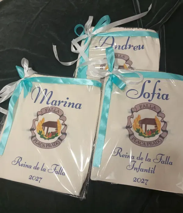 Tres cajas de regalo con cintas y los nombres Marina, Andrew y Sofia sobre una superficie oscura.