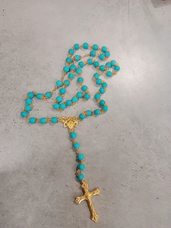 Cabeza de maniquí con bufanda azul y broches de colores, expuesta sobre un fondo de tela negra.