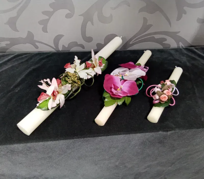 Tres ramilletes florales con flores rosas y blancas sobre tela blanca enrollada sobre un paño negro.
