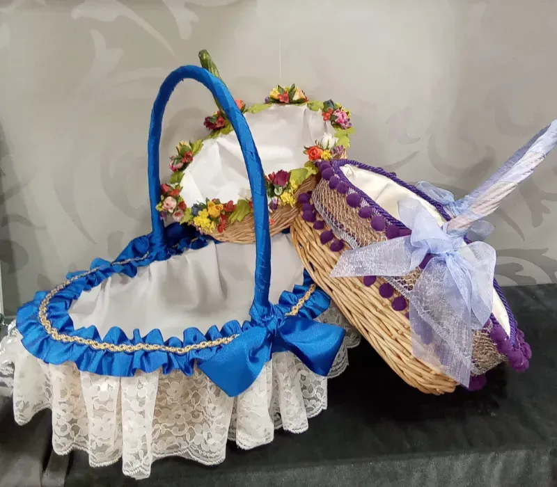 Cestas decorativas tejidas con encaje y ribetes de cinta en azul, blanco y morado sobre una superficie negra.